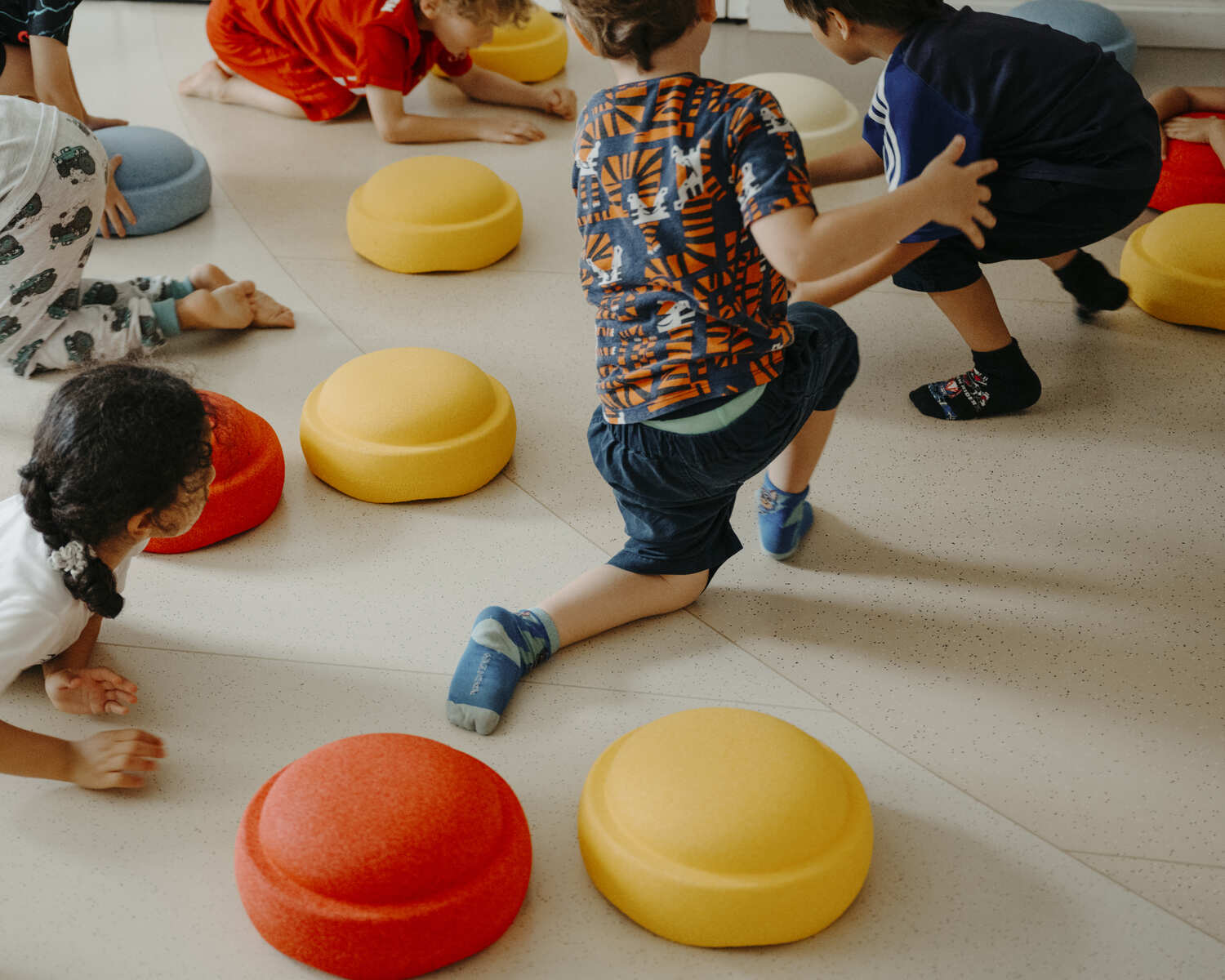 Kinder in der Kita spielen auf dem Boden mit bunten Stapelstein Bewegungselementen