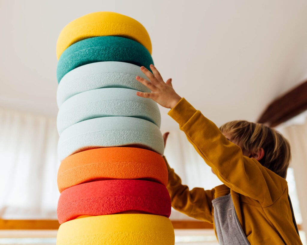 Kleinkind baut einen Turm aus Stapelsteinen zur motorischen Förderung