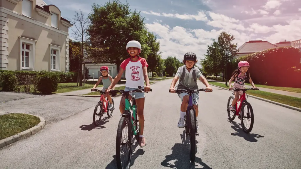 Kindergruppe fährt mit leichten Woom Fahrrädern durch eine Wohnstraße – Woom Bikes mieten